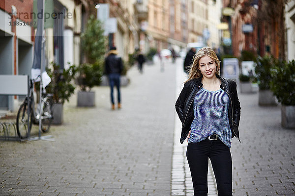 Portrait einer lächelnden jungen Frau in der Fußgängerzone