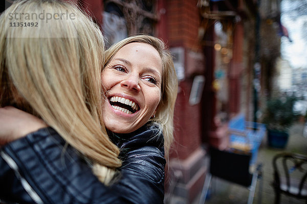 Zwei glückliche Frauen umarmen sich im Freien