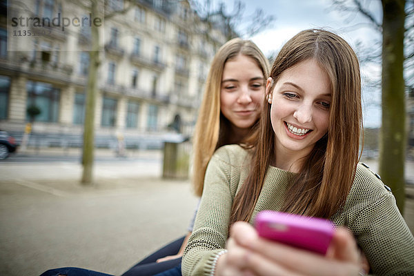 Zwei lächelnde junge Frauen mit Handy