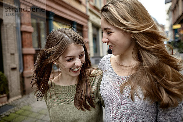 Zwei fröhliche junge Frauen machen einen Stadtbummel