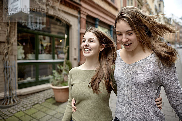Zwei fröhliche junge Frauen machen einen Stadtbummel