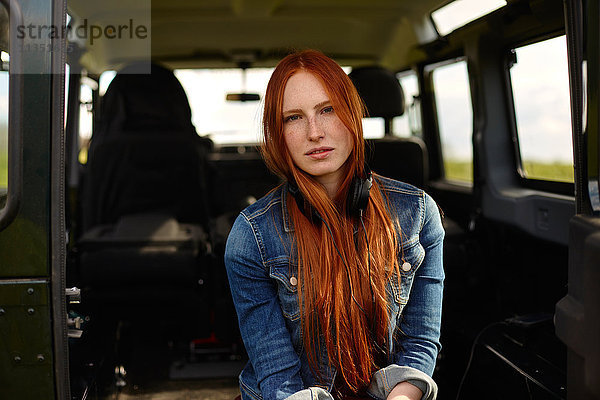 Portrait einer jungen Frau mit Kopfhörern im Auto