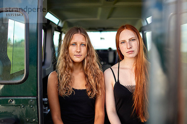 Zwei junge Frauen sitzen im Kofferraum eines Geländewagens