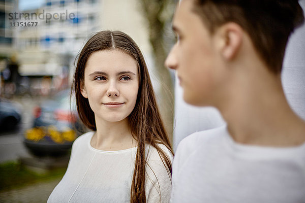 Lächelnde Teenagerin schaut auf Jungen im Freien