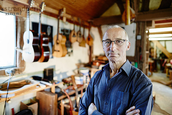 Portrait eines zuversichtlichen Gitarrenbauers in seiner Werkstatt