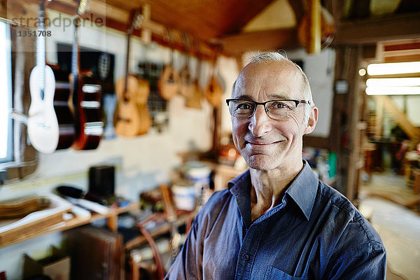 Portrait eines lächelnden Gitarrenbauers in seiner Werkstatt
