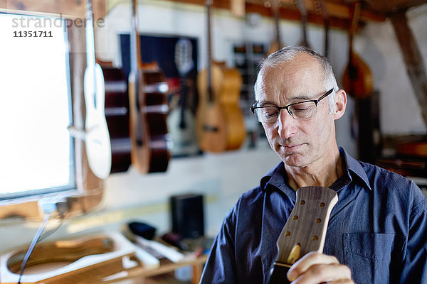 Gitarrenbauer untersucht eine Gitarre in seiner Werkstatt
