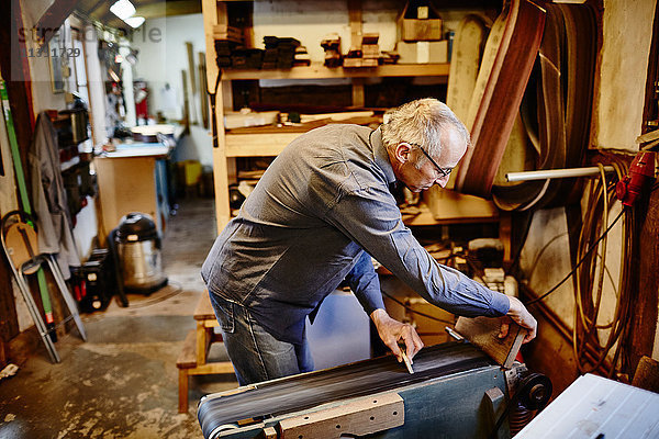 Handwerker benutzt eine Schleifmaschine in seiner Werkstatt