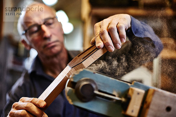 Gitarrenbauer schleift ein Griffbrett in seiner Werkstatt