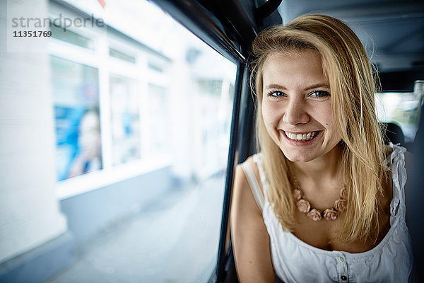 Portrait einer lächelnden jungen Frau in einem Auto