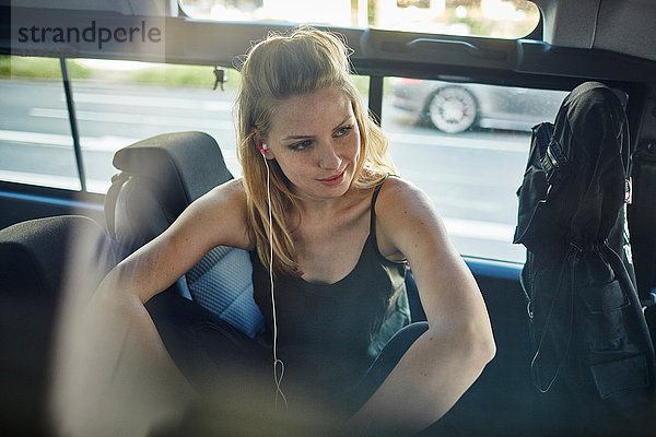 Junge Frau im Auto mit Ohrhörer