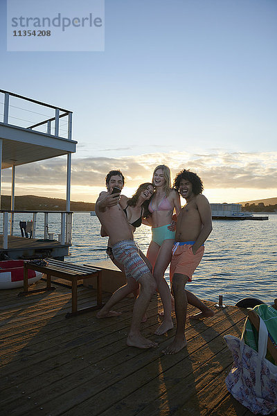 Verspielte junge erwachsene Freunde  die Selfie mit Fotohandy auf dem Sommerhausboot mitnehmen.