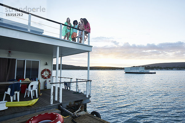 Junge erwachsene Freunde  die auf dem Deck des Sommerhausbootes auf dem Meer herumhängen