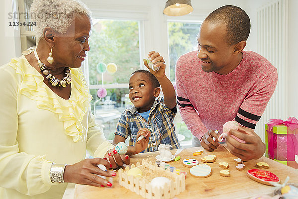 Mehrgenerationen-Familie dekoriert Ostereier und Kekse in der Küche