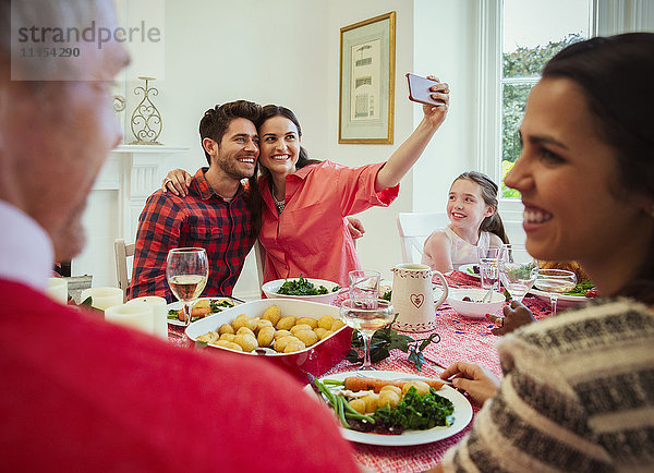 Paar mit Fotohandy  das Selfie am Weihnachtstisch nimmt.