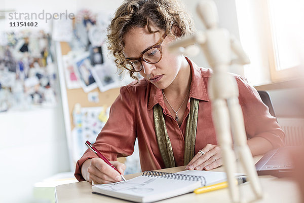 Fokussiertes weibliches Design professionelles Skizzieren im Notebook im Büro