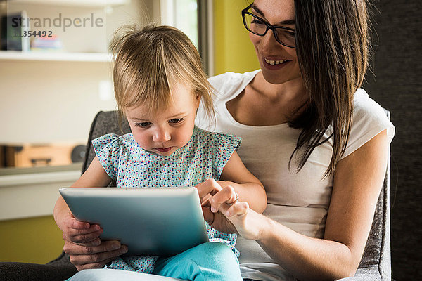 Mutter lehrt Tochter  das digitale Tablett zu Hause zu benutzen.