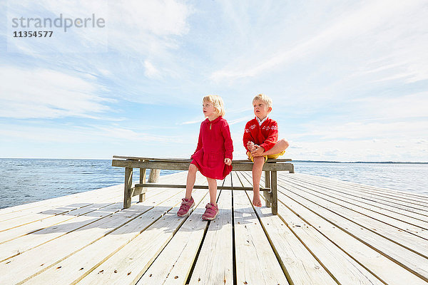 Zwei junge Freunde sitzen auf einer Bank am Holzpier