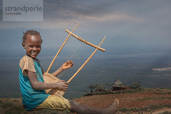 Junges äthiopisches Mädchen spielt ein selbstgebautes Instrument  Lalibela  Äthiopien