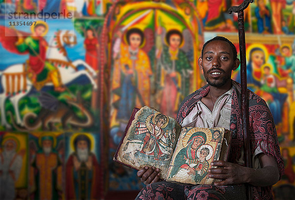 Priester zeigt ein altes religiöses Buch in einem orthodoxen Kloster  Tigray  Äthiopien