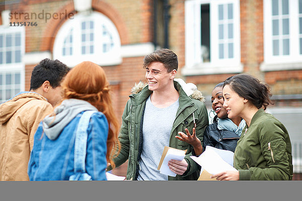 Glückliche junge erwachsene College-Studenten gratulieren sich gegenseitig zu ihren Prüfungsergebnissen auf dem Campus