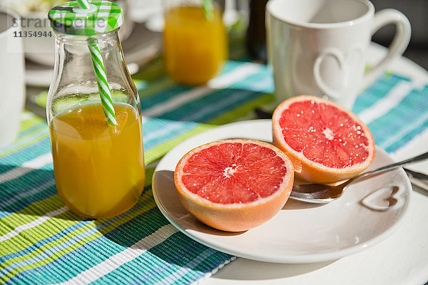 Halbe Grapefruit und eine Flasche Orangensaft