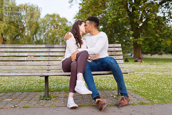 Junges Paar auf der Parkbank beim Küssen