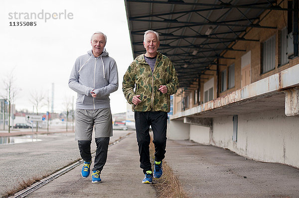 Ältere Freunde in Sportkleidung beim Joggen nebeneinander