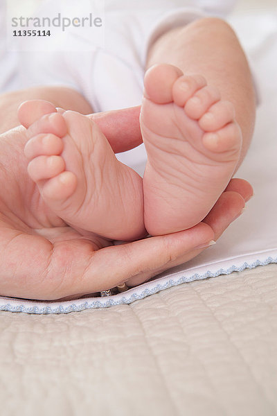 Mütter halten die Hand Baby Jungen Füße