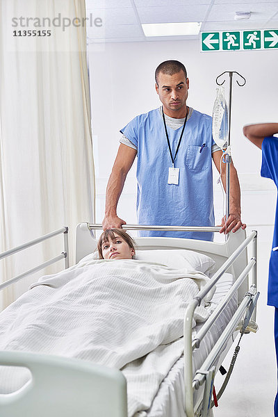 Krankenschwester schiebt Patient im Krankenhausbett