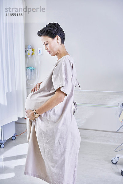 Seitenansicht einer schwangeren Frau im Krankenhauskittel