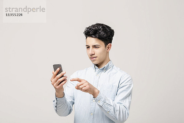 Junger Mann schreibt SMS auf Smartphone