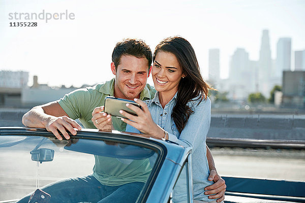 Paar in Cabriolet mit Blick auf Smartphone  Los Angeles  Kalifornien  USA