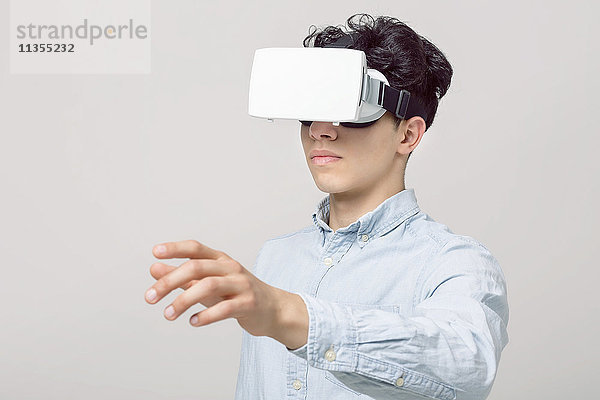 Junger Mann mit Virtual-Reality-Headset  der den Arm ausstreckt