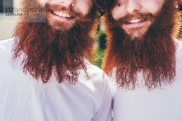 Beschnittenes Porträt junger männlicher Hipster-Zwillinge mit roten Bärten und weißen T-Shirts