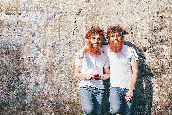 Porträt von jungen männlichen Hipster-Zwillingen mit roten Bärten vor der Wand stehend