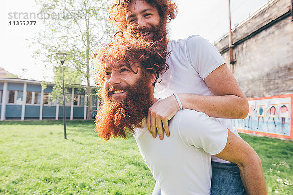 Junge männliche Hipster-Zwillinge mit roten Bärten schweinchend im Park