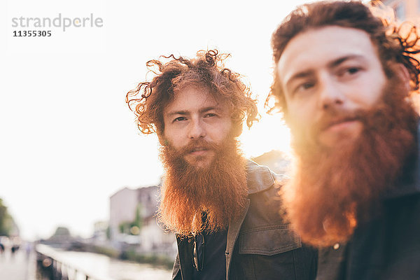 Junge männliche Hipster-Zwillinge mit roten Haaren und Bärten am Kanalufer