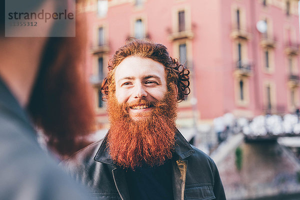 Junge männliche Hipster-Zwillinge mit roten Haaren und Bärten reden auf der Straße