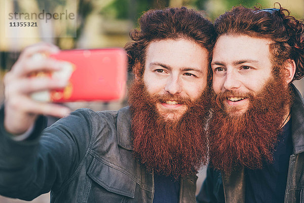 Junge männliche Hipster-Zwillinge mit roten Haaren und Bärten nehmen Smartphone Selfie