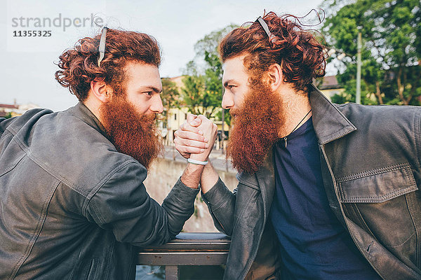 Junge männliche Hipster-Zwillinge mit roten Haaren und Bärte Armdrücken auf Brücke