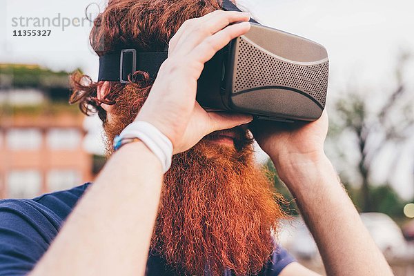 Junger männlicher Hipster mit roten Haaren und Bart im Virtual Reality Headset