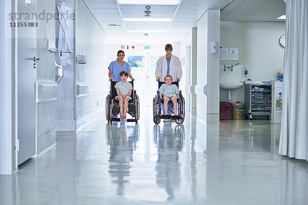 Sanitäter schieben Jungen-Patienten im Rollstuhl auf der Kinderstation eines Krankenhauses