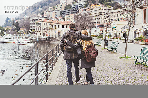 Rückansicht eines jungen Paares beim Spaziergang am Seeufer  Comer See  Italien