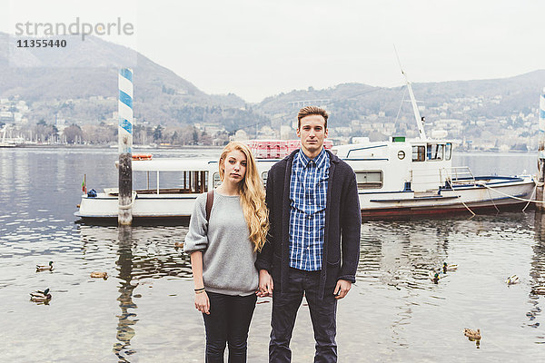 Porträt eines jungen Paares beim Händehalten am nebligen Comer See  Italien