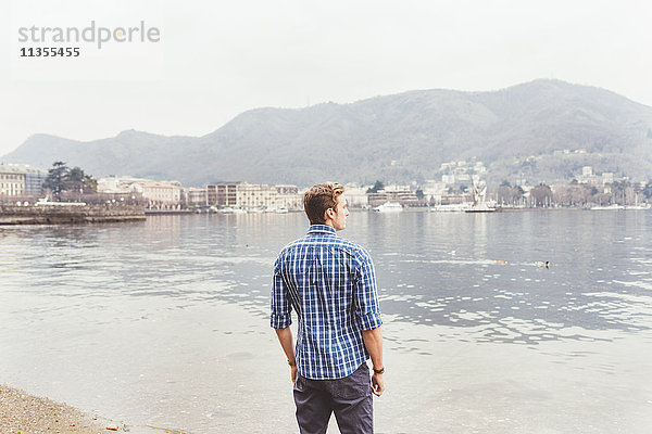 Junger Mann schaut vom Seeufer aus  Comer See  Italien