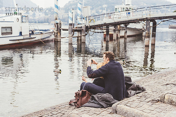 Junges Paar beim Fotografieren vom Seeufer aus  Comer See  Italien