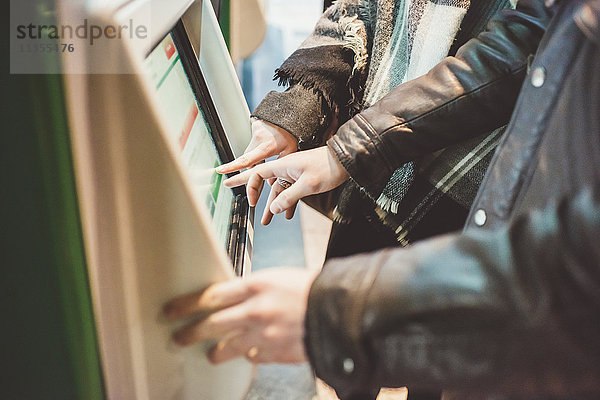 Junges Paar kauft Zugfahrkarten am Touchscreen-Fahrkartenautomaten