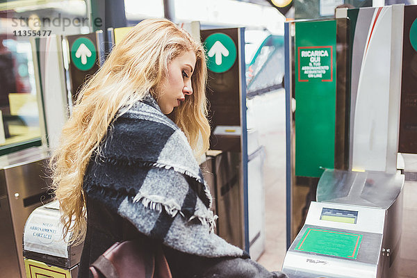 Junge Frau benutzt Fahrkartenschranke im Bahnhof