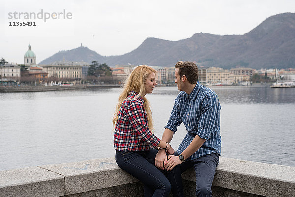 Romantisches junges Paar hält Hände an der Hafenmauer  Comer See  Italien